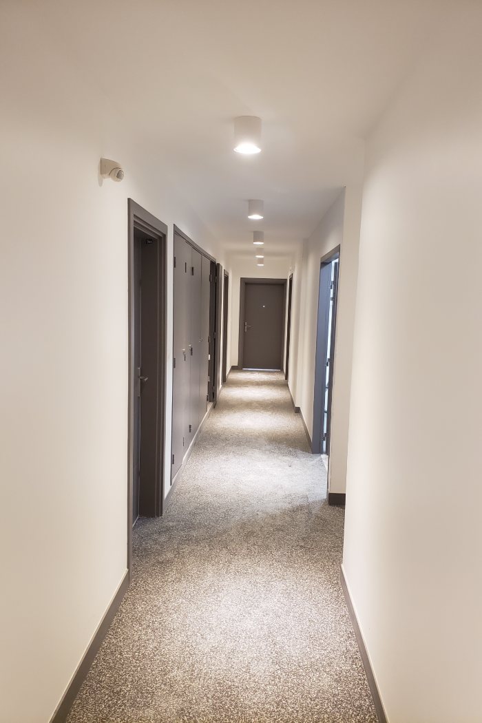 Couloir d'étage d'immeuble : plafonniers en saillie allumés et détecteur de présence, installés par GK ELEC 38.