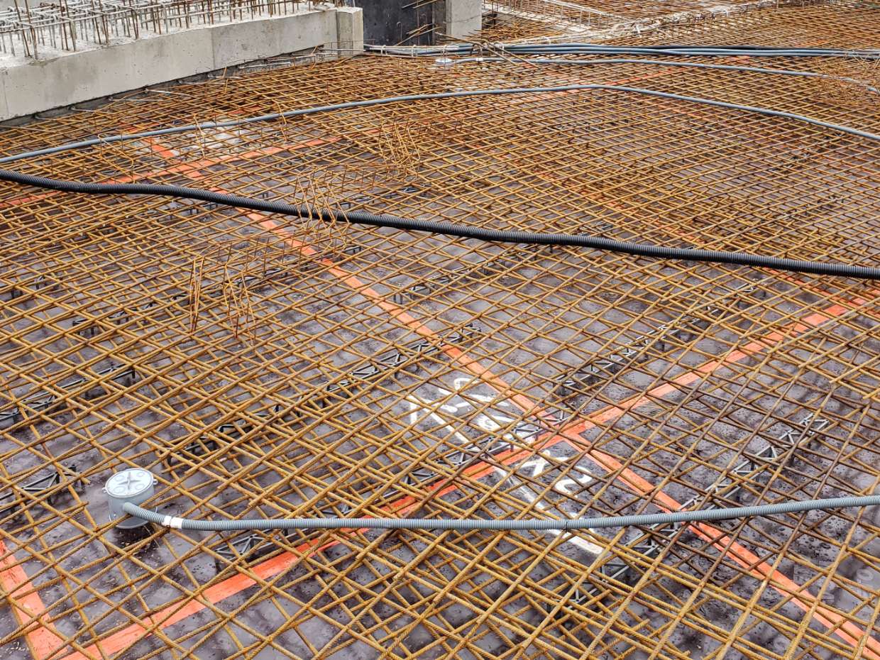 Gaines et boîte de sol fixées dans le ferraillage d'une dalle d'immeuble neuf, prêtes pour le coulage.