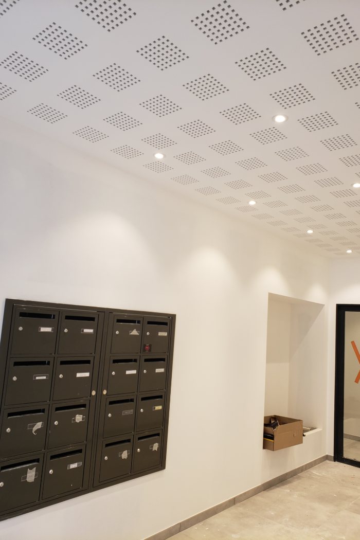 Hall d'immeuble neuf : spots encastrés dans un faux plafond acoustique, allumés, posés par GK ELEC 38.
